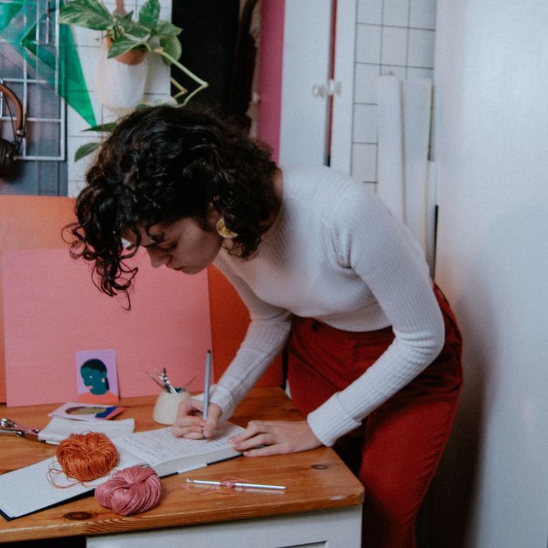 Sandra Tenorio tomando notas en su mesa, con un ovillo y un ganchillo al lado